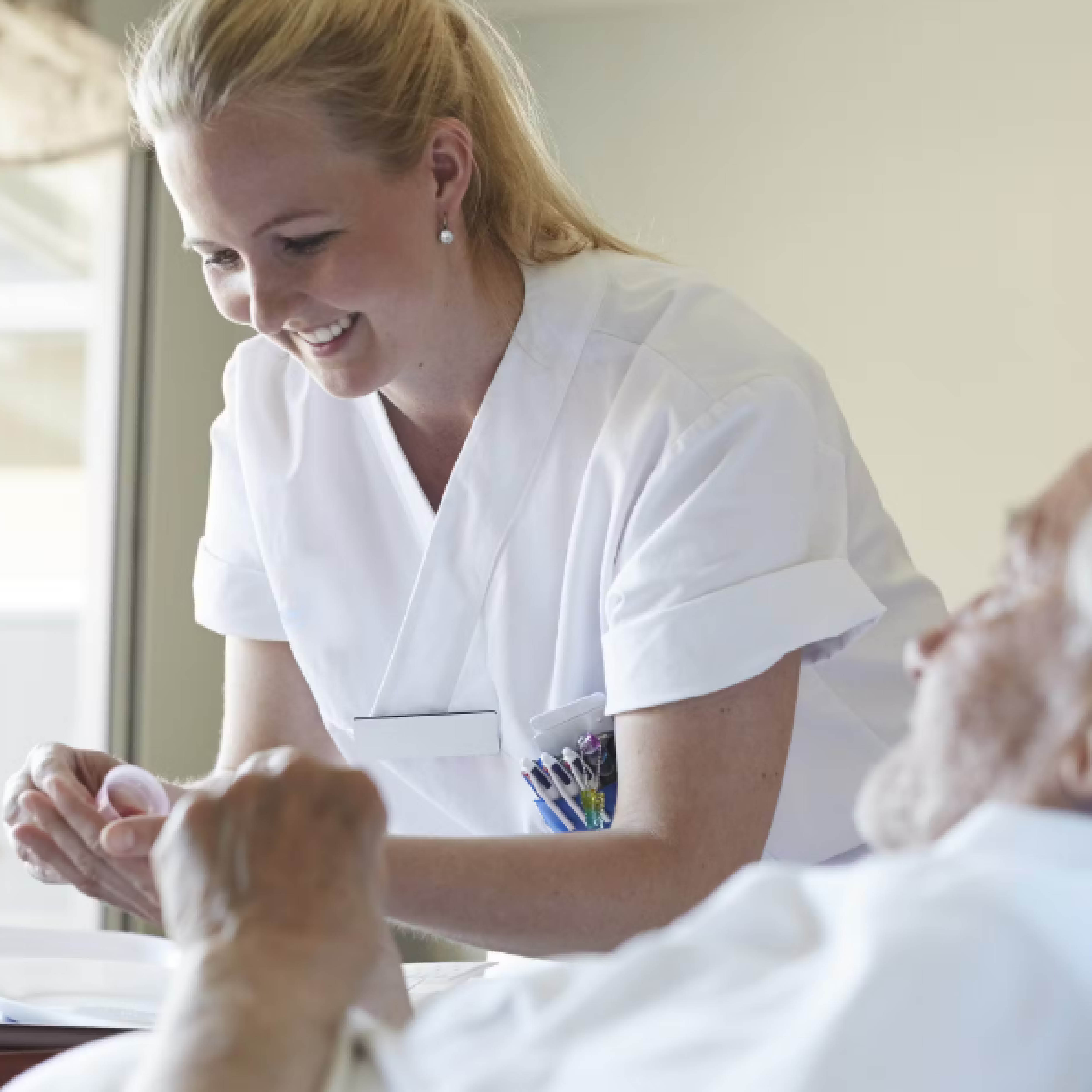 Een verpleegster aan het bed van een patiënt, een oude man