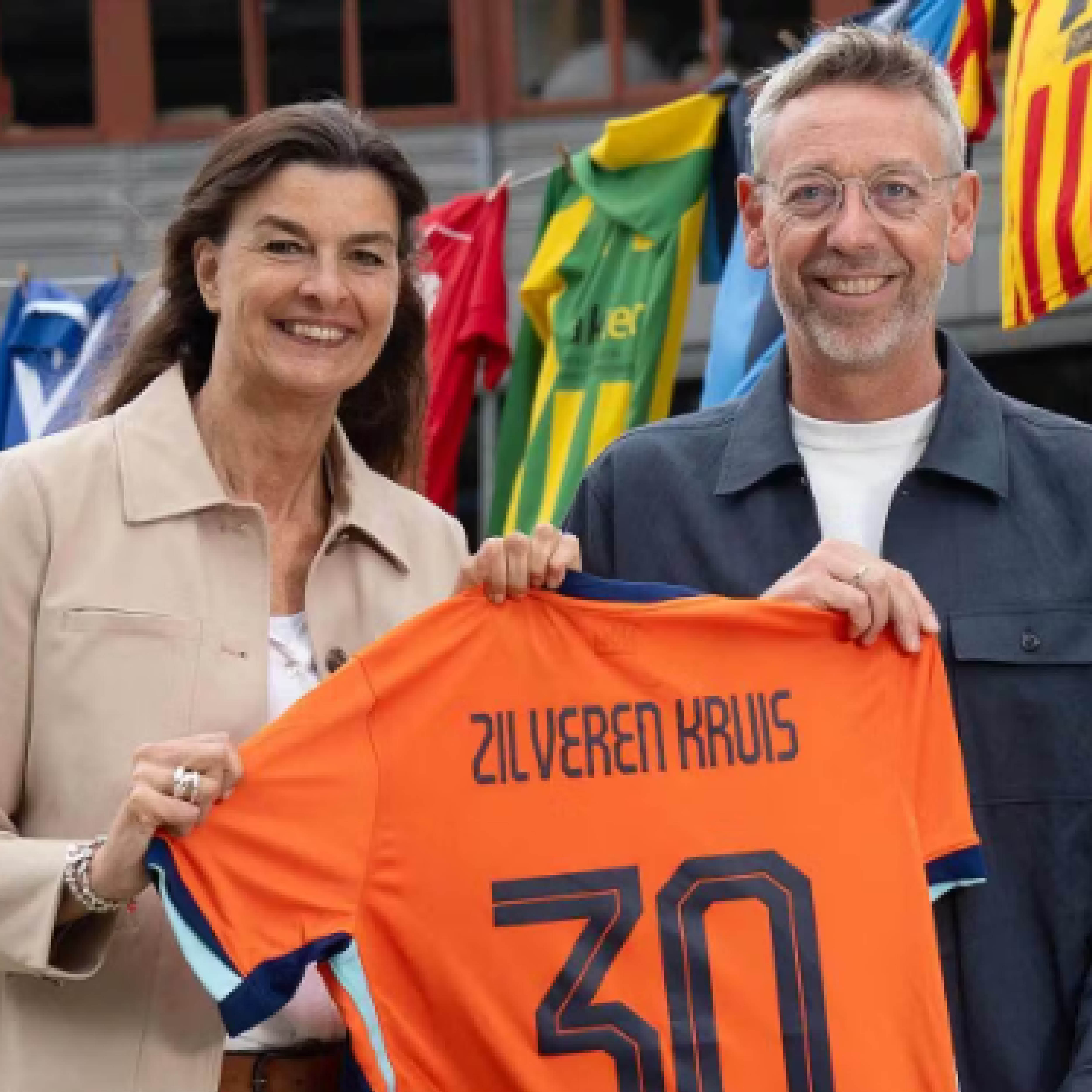 Georgette Fijneman van Zilveren Kruis met Jan Dirk van der Zee van de KNVB. Ze houden een oranjeshirt vast met Zilveren Kruis op de achterkant