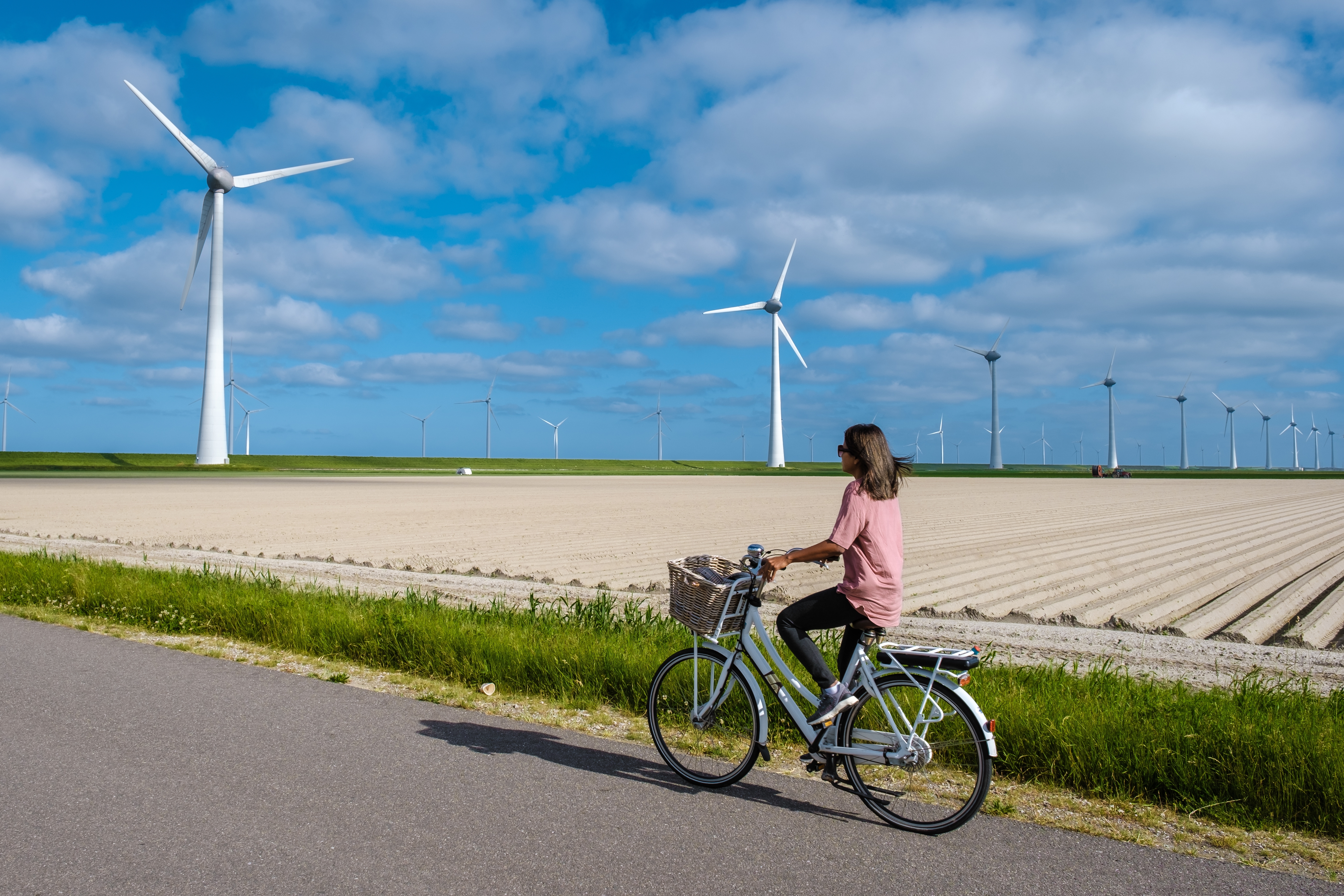 Vrouw fietst in een polderlandschap, je ziet een windmolen