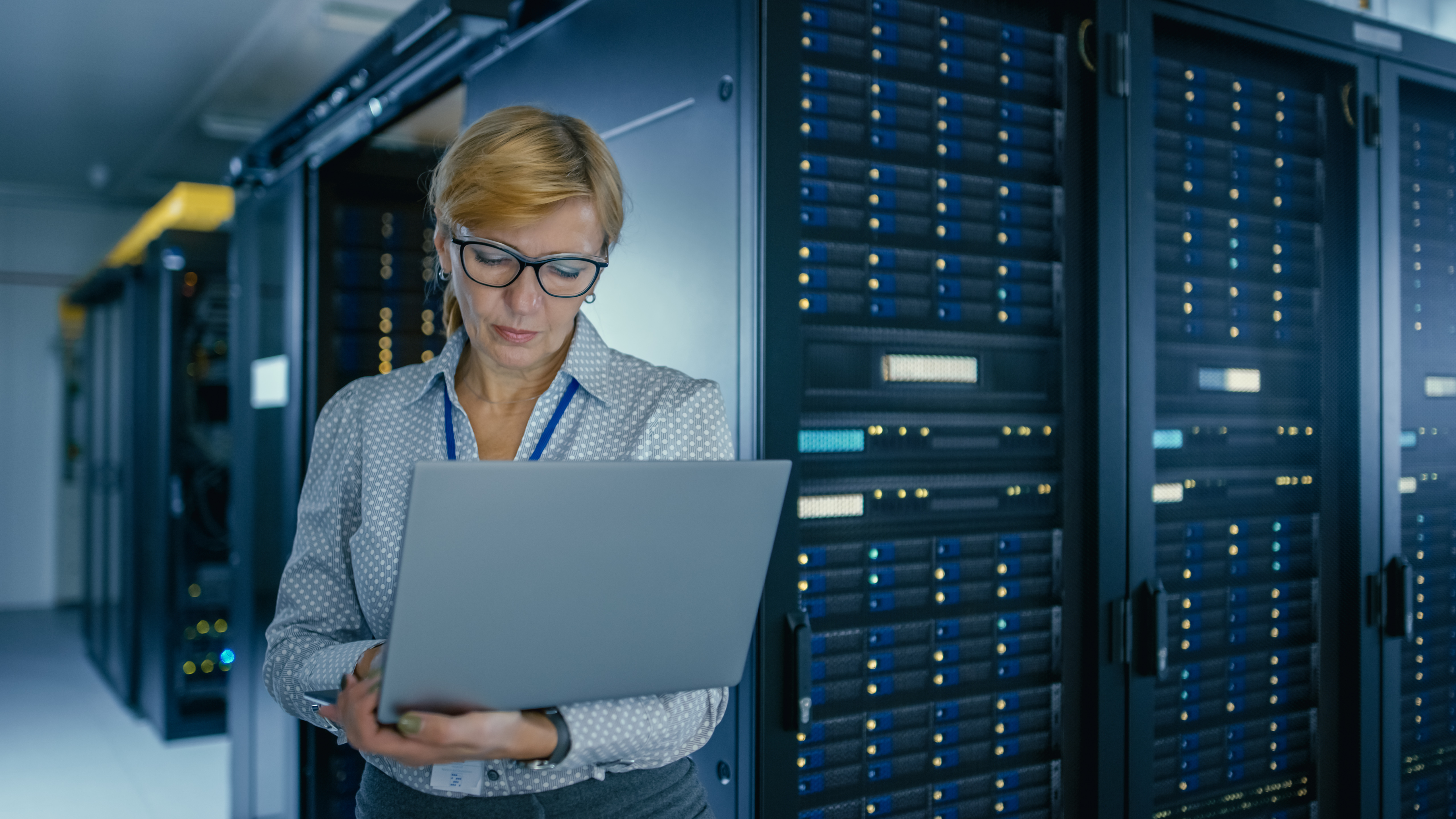 Vrouw staat met laptop in een datacentrum