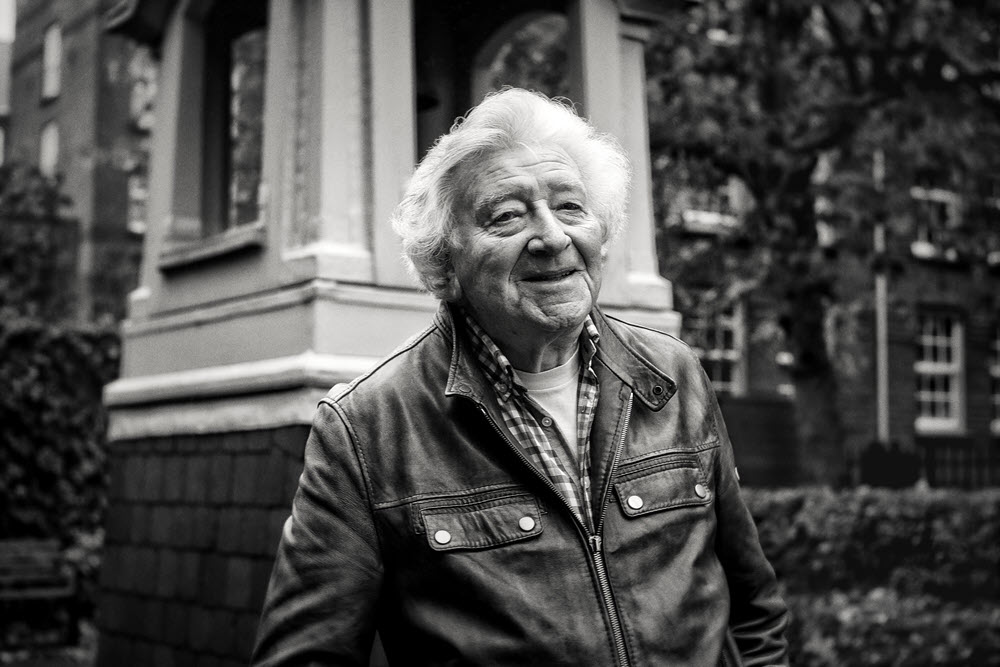 Oudere man met leren jasje voor het gebouw van De Makroon