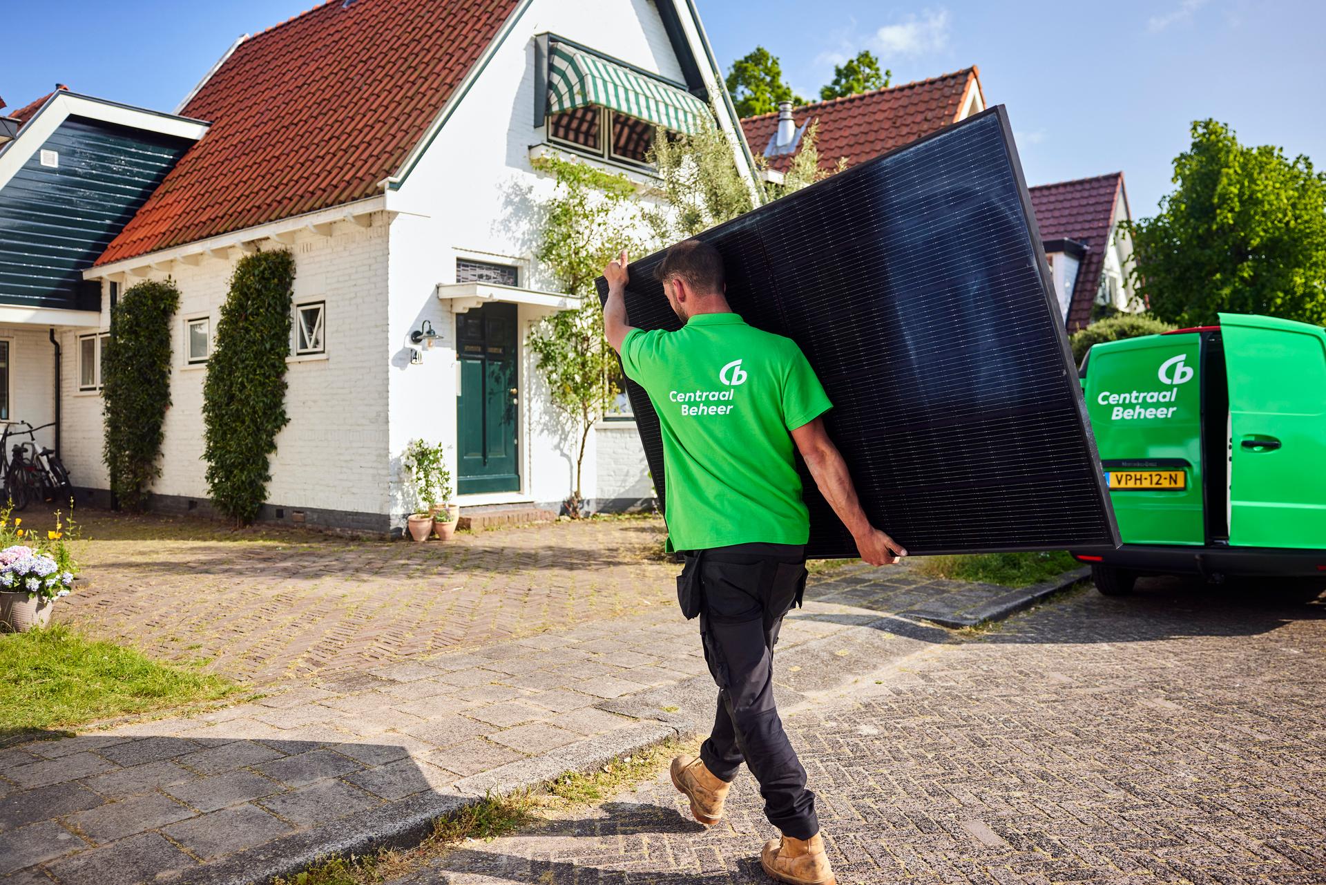 Zonnepanelen installateurs lopen met een zonnepaneel in de hand naar een huis voor installatie
