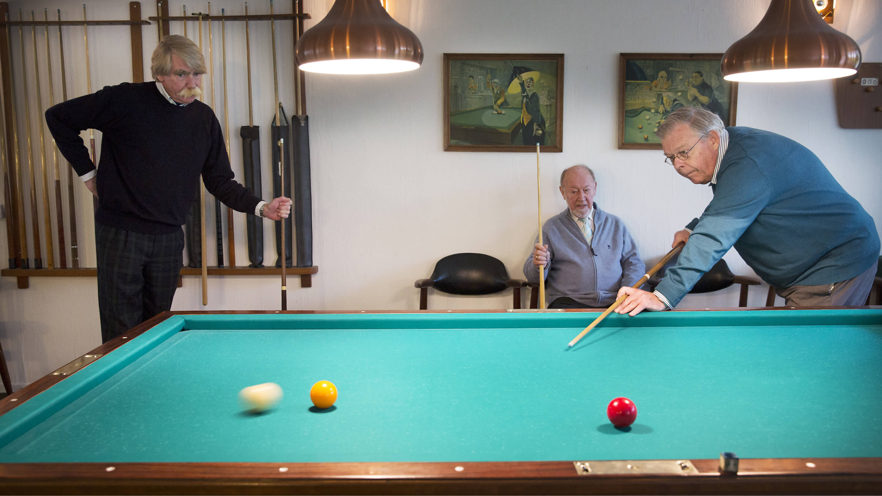 Drie oudere mannen zijn aan het biljarten