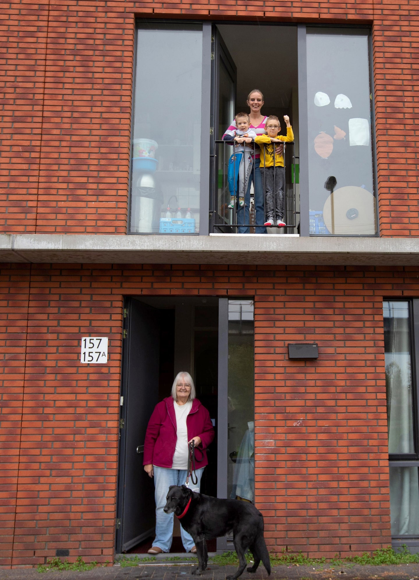 Een kangeroewoning van twee verdiepingen. Je ziet boven het gezin en onder oma met hond.