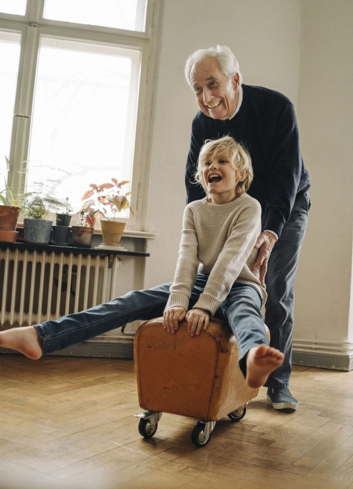 Opa duwt kleinzoon vooruit op karretje in de woonkamer