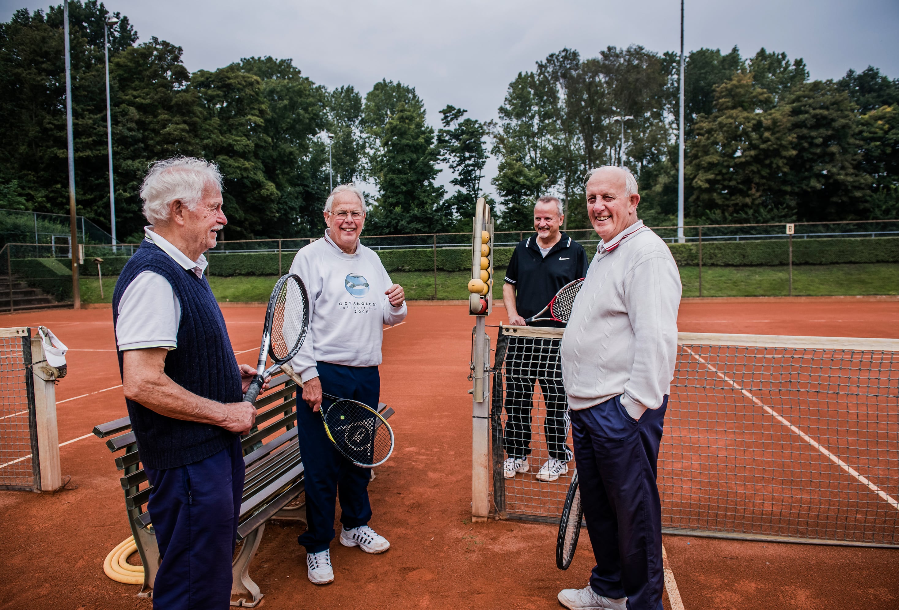 4 oudere mannen op de tennisbaan.