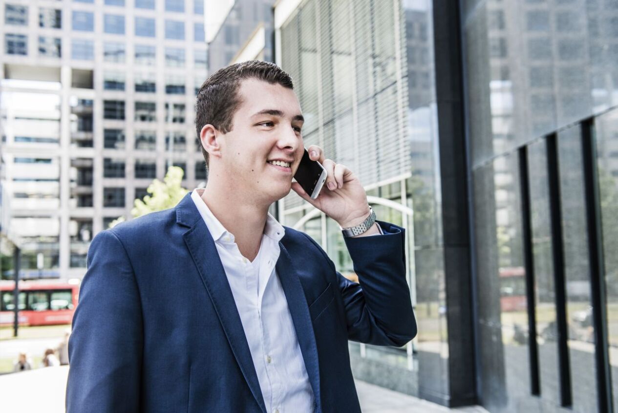 Een man is vlak voor een kantoorpand buiten aan het bellen