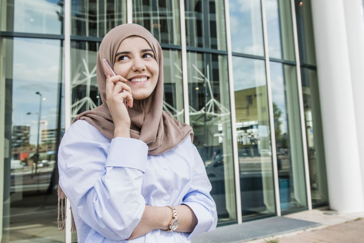 Een vrouw is aan het bellen, ze draagt een hoofddoek