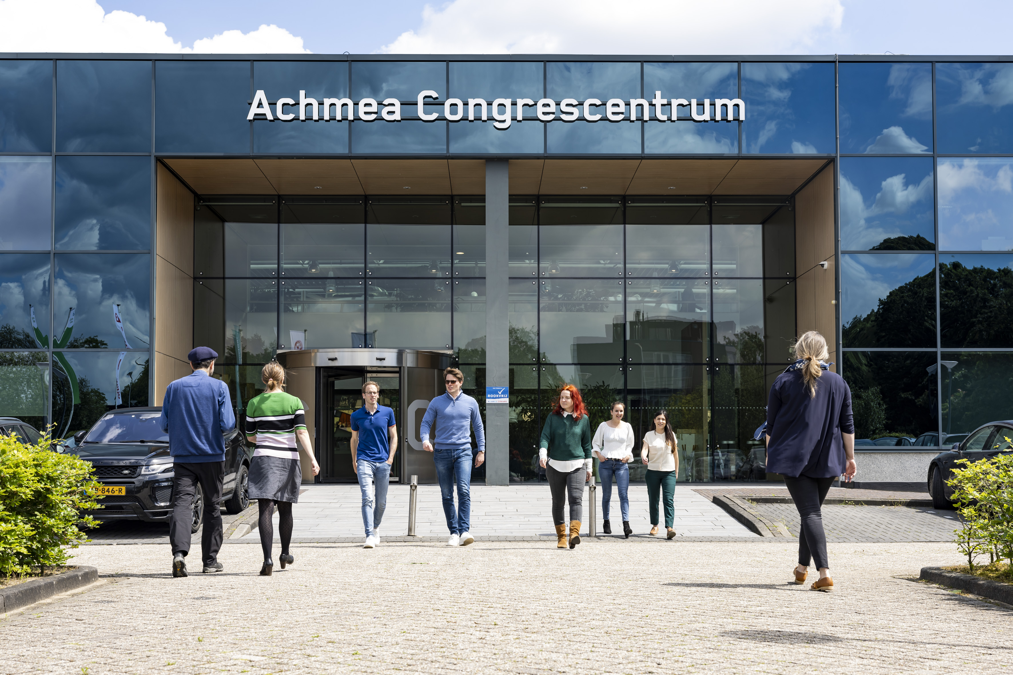 Ingang van het congrescentrum van Achmea in Zeist met lopende mensen